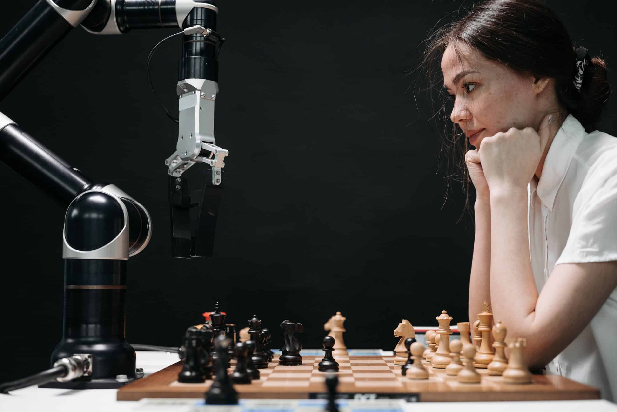 Vrouw speelt schaak tegen een robotarm, als symbool voor de invloed van AI op menselijk werk. Kopiëren
